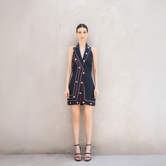 A woman wearing the Pulse dress, a sleeveless tailored dress made of Fastoni fabric with red and white laser-cut lines and golden buttons.