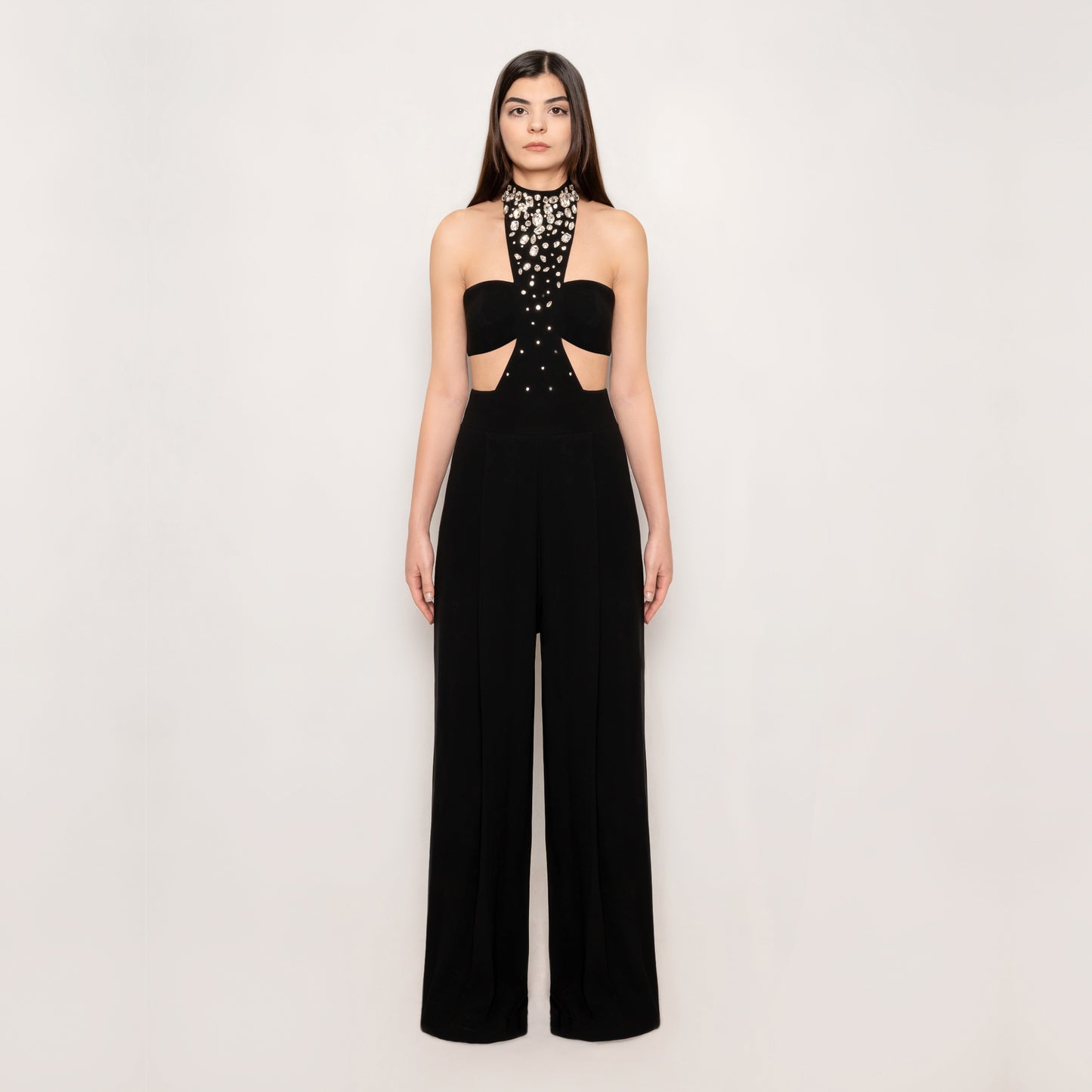 Front view of the Crystal Jumpsuit by Tehran, featuring a chic halterneck design with a tasteful side slit. The ruched detailing and high-waisted silhouette create an elegant and flattering look in black.