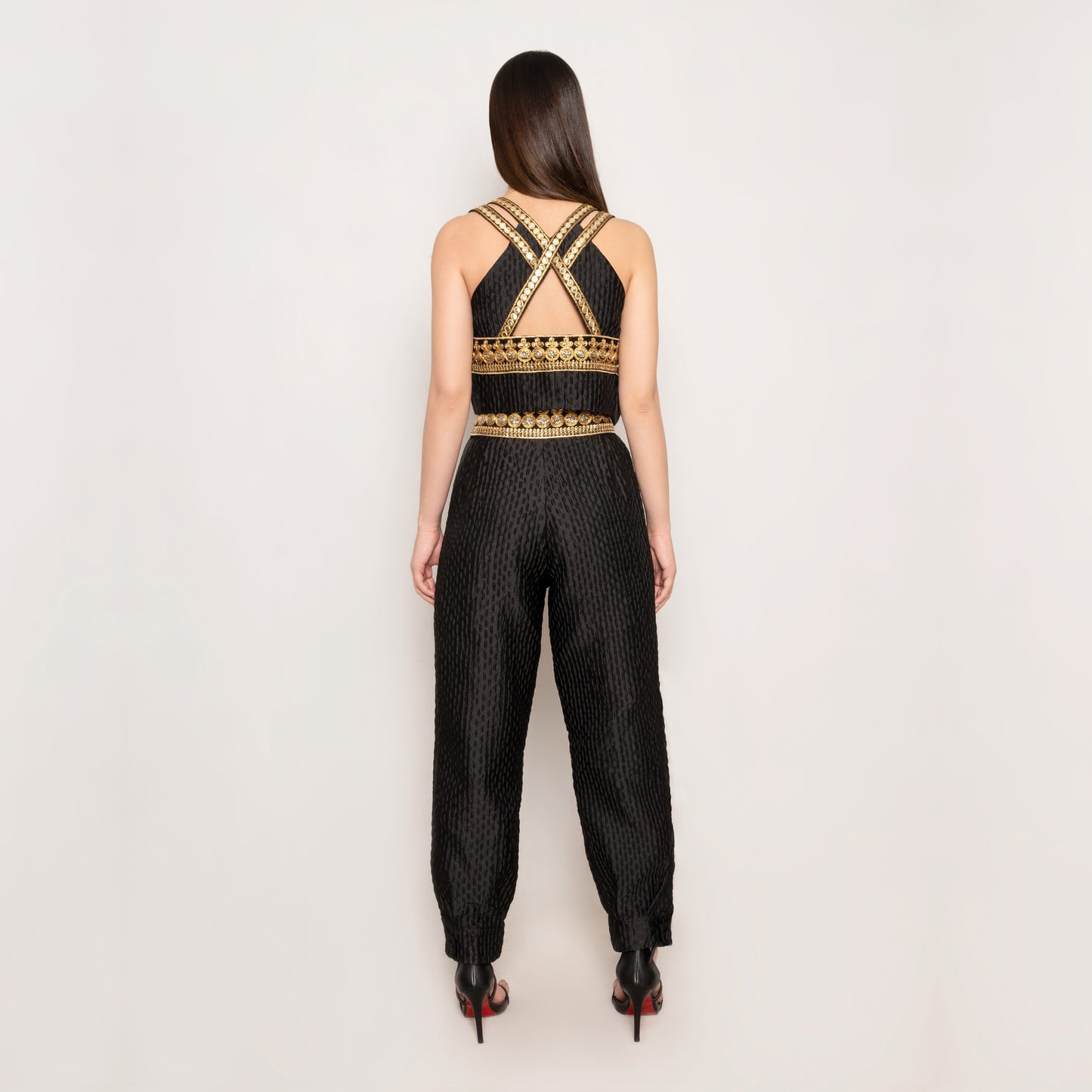 Back view of the "Golden Nomad Set" by Tehran Official, highlighting the plunging V-neckline with a keyhole detail on the vest. The sleek, tailored silhouette of the jacquard fabric showcases the structured fit and elegant trims. This angle emphasizes the refined craftsmanship and sophisticated design details that define this bold and modern black vest and pants set.