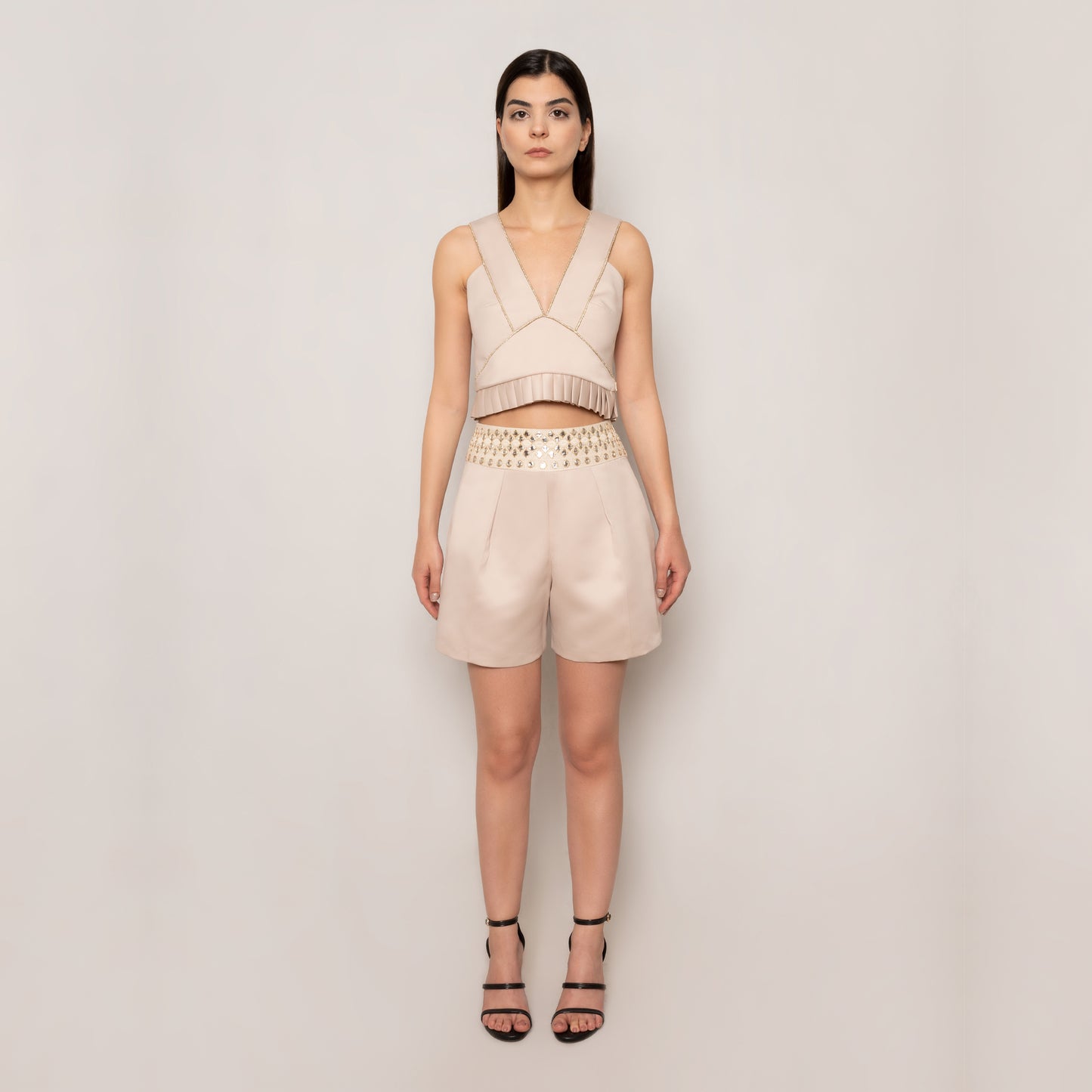 Front view of the Top & Shorts Set by Tehran in beige, highlighting the sophisticated V-neck sleeveless top with refined pleated detailing and modern tailored shorts, perfect for warm-weather occasions.