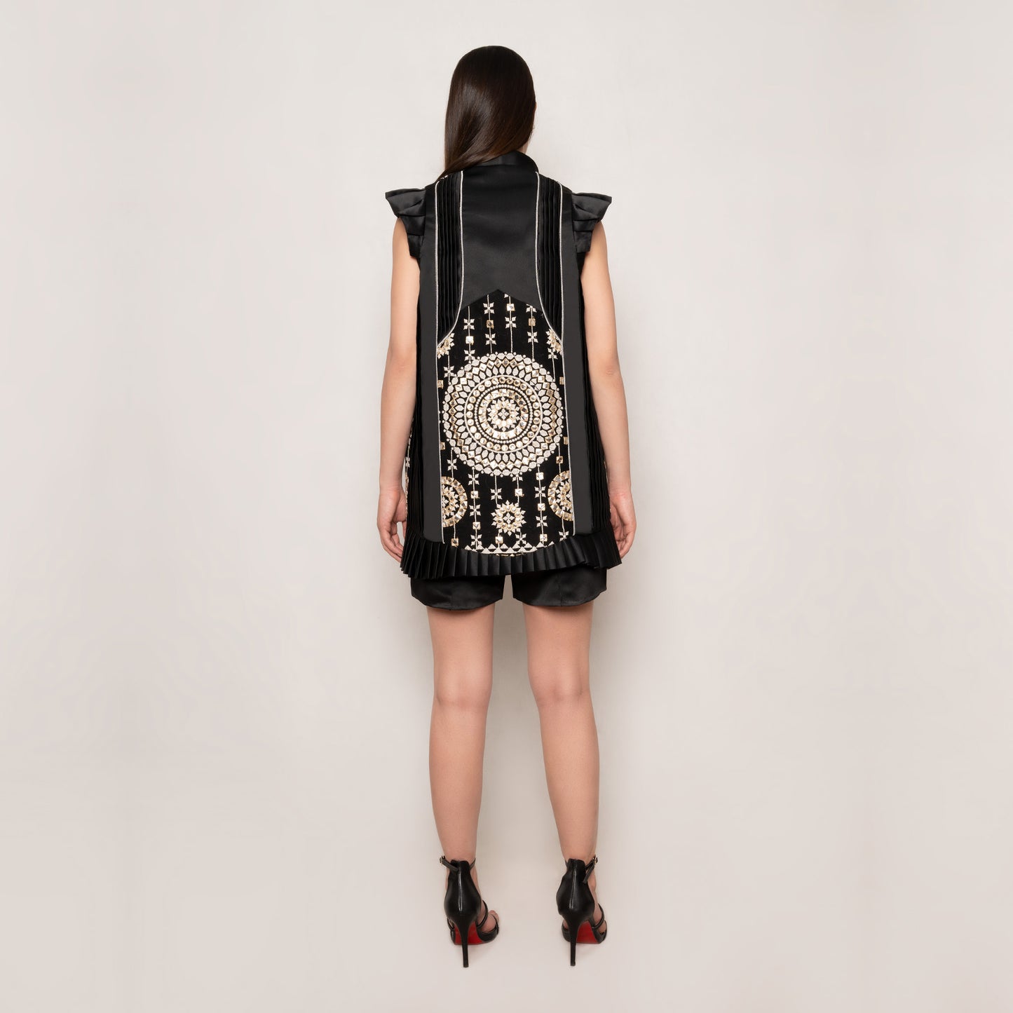 Back view of the Mirror Magic Long Vest by Tehran in black, featuring luxurious silk with intricate mirror work on a velvet base. The sleeveless design and pleated detailing enhance its refined silhouette.