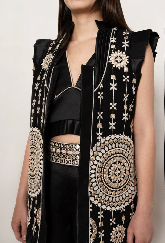 Close-up view of the "Mirror Magic Long Vest" by Tehran Official in black silk, highlighting intricate mirror work, pleated detailing, and the luxurious craftsmanship. The rich texture of the silk combined with a velvet or linen base showcases traditional artistry blended with modern elegance, emphasizing premium quality and refined design elements.